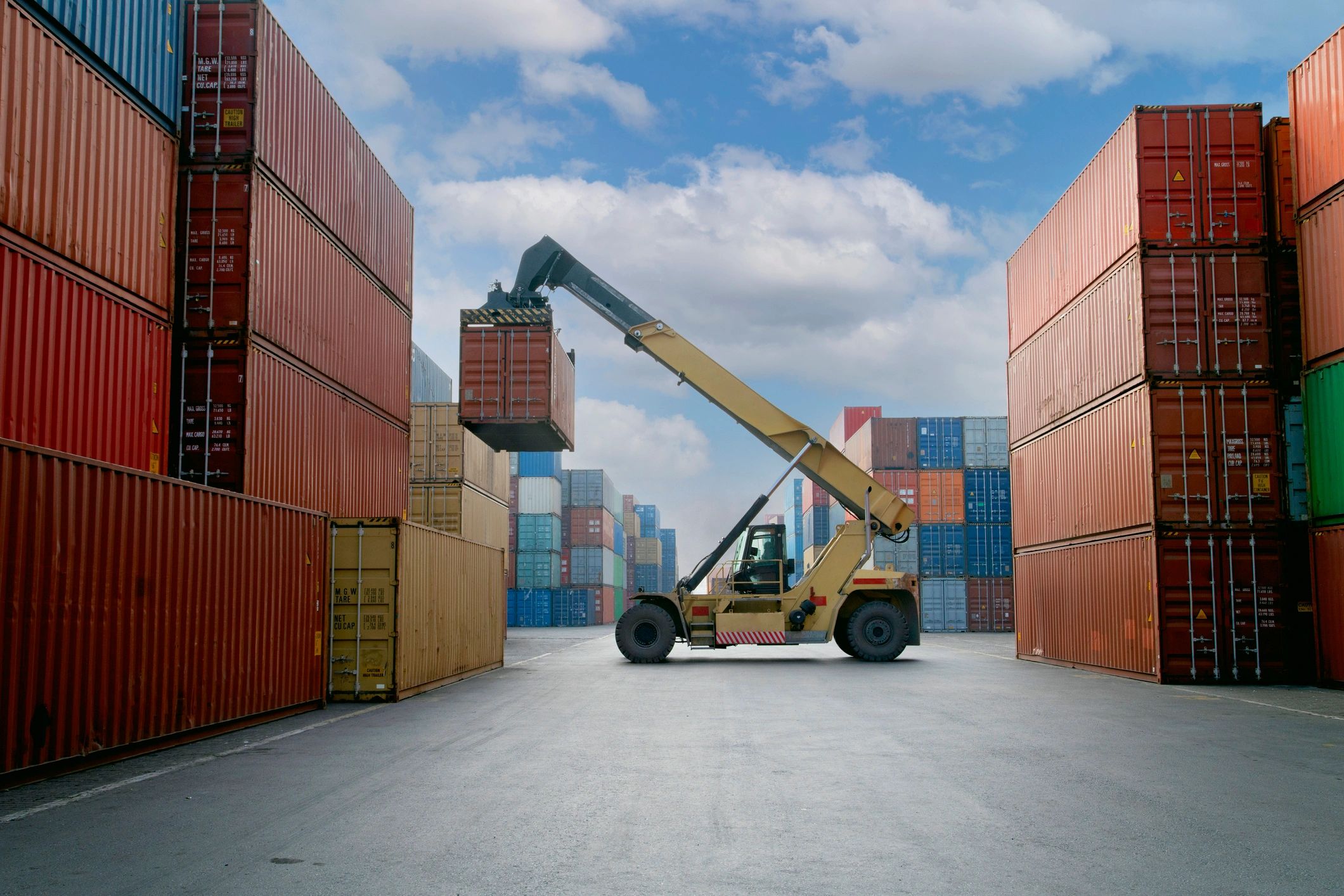 Forklift moving a shipping container in a busy port.