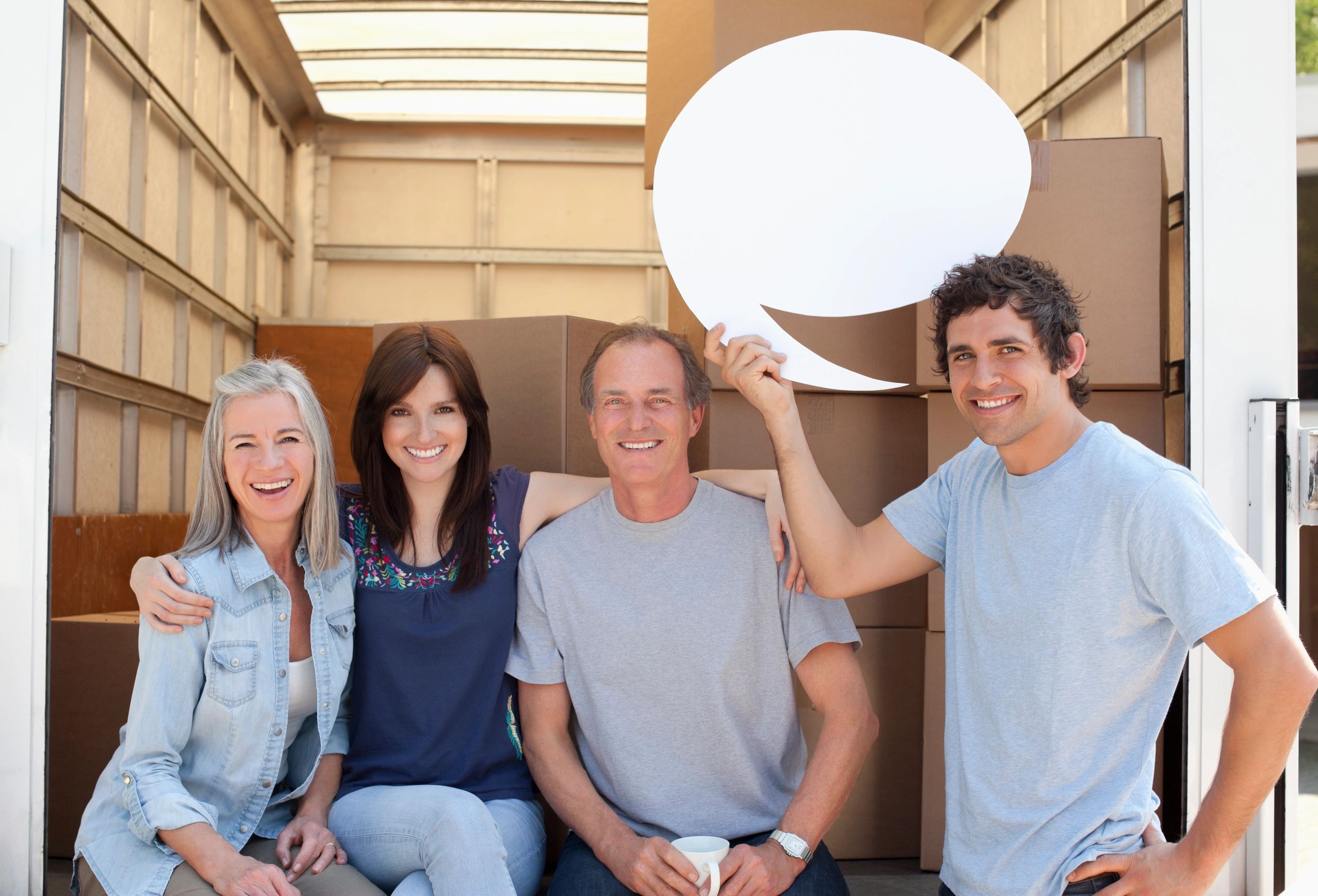 A happy family of four sitting together, with a young man holding a blank speech bubble.