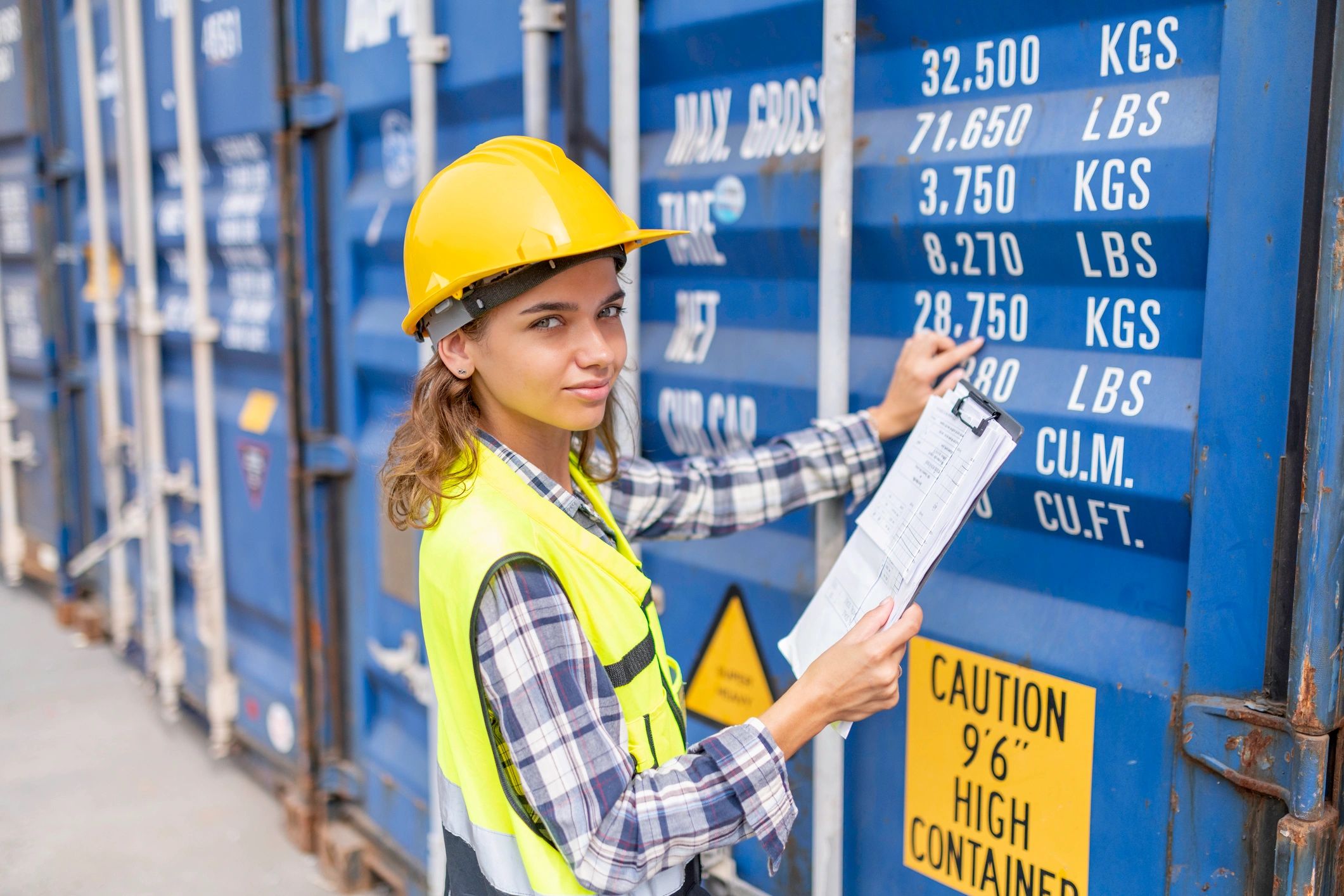 Female engineer inspecting a hazardous container at a shipping yard.